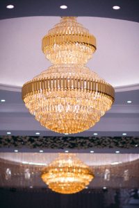 Stunning crystal chandelier hanging in a luxurious indoor venue with soft lighting.