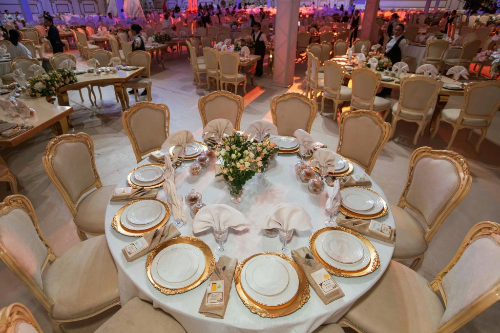 Luxurious wedding reception with elegantly decorated tables and chairs in an opulent setting.